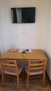 mesa de madera con 2 sillas y TV en la pared en Izvorul Maleii, en Petrila