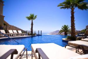een zwembad met stoelen en palmbomen en de oceaan bij Incredible 3BR Ocean View Villa in Cabo San Lucas in Cabo San Lucas