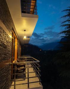 un balcón con vistas a las montañas por la noche en The Forest Pinnacle Hostel and Café, Old Manali, en Bashist