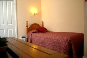 a bedroom with a bed and a table and a door at Gatwick Turret Guest House in Horley