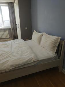 een bed met witte lakens en kussens in een kamer bij Loftik Apartments Shevchenko street in Alma-Ata