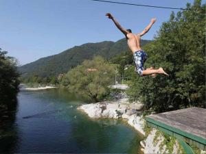 un hombre saltando de un puente sobre un río en Ferienwohnung für 4 Personen ca 72 qm in Slap ob Idrijci, Küstenland Slowenien en Slap ob Idrijci