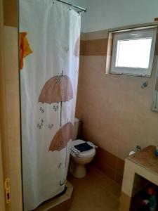 a bathroom with a toilet and an umbrella shower curtain at Katerina's House in Sitia