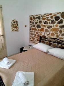 a bed in a room with a stone wall at Katerina's House in Sitia