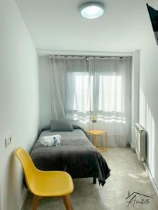 a bedroom with a bed and a yellow chair at ACUBILLO in Palas de Rei