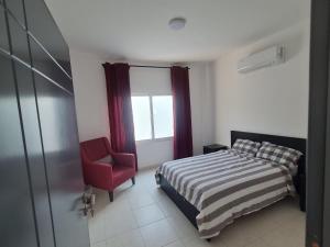 a bedroom with a bed and a chair and a window at Jimi Chalet in Al Kafrayn