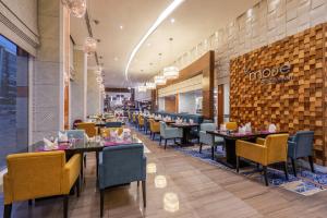a dining room with tables and chairs in a restaurant at Novotel Suites Riyadh Olaya in Riyadh