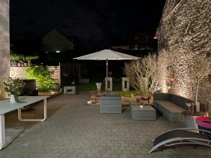 un patio con sombrilla, mesas y sillas en Les Myosotis Chambres d'hôtes - Sarreguemines, en Zetting