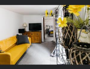 a living room with a yellow couch and a tv at Alltavona House in Oban