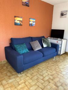 Sofá azul en la sala de estar con TV en Camargue Village Sun and Beach #2 5 Personnes, en Le Grau-du-Roi