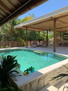 a swimming pool in a backyard with a pergola at Kubu Shanti in Gili Meno