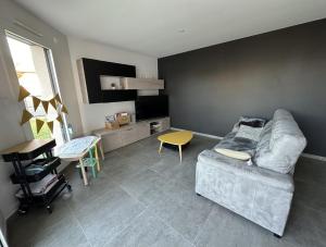 a living room with a couch and a tv at Chambres 24h du Mans in Mulsanne