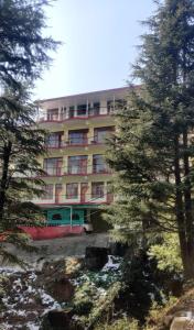 a large building with trees in front of it at Vibes by Vicctoria House in McLeod Ganj