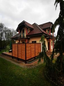 a house with a fence in front of it at Domek wypoczynkowy Zielonka z JACUZZI in Szczytno