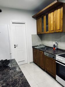 a kitchen with wooden cabinets and a black counter top at Apartman Magnolia in Novi Pazar