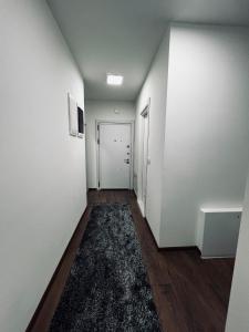 an empty hallway with white walls and a rug at Apartman Magnolia in Novi Pazar