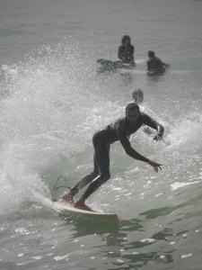 un hombre montando una ola en una tabla de surf en el agua en Olympe Surf & Yoga en Tamraght Ouzdar