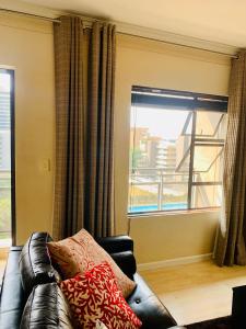 ein Wohnzimmer mit einem Ledersofa und einem Fenster in der Unterkunft The Westpoint Sandton Charm on 4th Floor in Johannesburg
