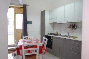 a kitchen with white cabinets and a table with chairs at """ Holiday Properties Sicilian Central """ in Avola