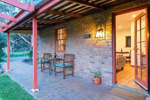 a patio with a brick wall and a table and chairs at Blueberry Farm Cottage in Willunga