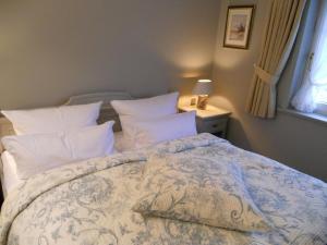1 dormitorio con 1 cama grande con almohadas blancas en Ferienwohnung für 2 Personen ca 55 qm in Munkmarsch, Nordfriesische Inseln Sylt - a87454, en Munkmarsch