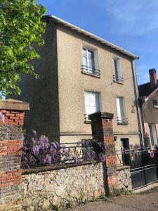 una casa con una valla de piedra y flores púrpuras en La maison Janisse, en Limoges