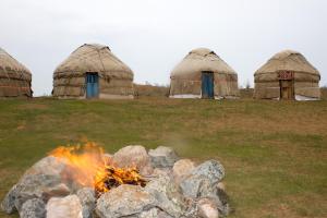 a fire pit in a field with three domes at Yurt Stay Family Khansar in Nurota