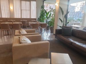 a living room with couches and tables and a restaurant at Hotel Bianca Vela in Rimini