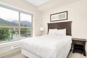 Un dormitorio blanco con una cama grande y una ventana en Lakeview Majesty: Lavish 7-BR Penthouse Retreat With Rooftop Panorama, en Harrison Hot Springs