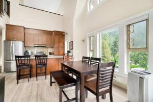 a kitchen with a wooden table and chairs and a counter at Lakeview Majesty: Lavish 7-BR Penthouse Retreat With Rooftop Panorama in Harrison Hot Springs