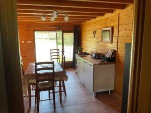 eine kleine Küche mit einem Tisch, einem Tisch und Stühlen in der Unterkunft Annexe de ferme cosy à 15 min de Gérardmer,Ventron et La Bresse in Thiéfosse