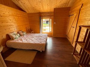 ein Schlafzimmer mit einem Bett in einer Holzhütte in der Unterkunft Annexe de ferme cosy à 15 min de Gérardmer,Ventron et La Bresse in Thiéfosse