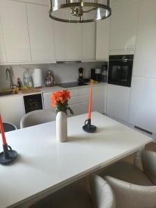 a white table with a vase with orange flowers on it at Abbey Road Luxury Modern Flat w Historic Vibes in London