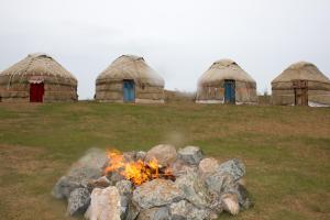 een vuurplaats in een veld met drie koepels bij Yurt Stay Family Khansar in Nurota