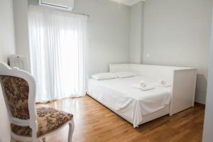 um quarto branco com uma cama e uma cadeira em Brand new apt in Zografou em Atenas