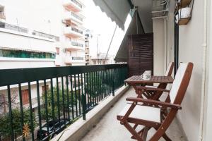 una silla de madera sentada en un balcón con una mesa en Brand new apt in Zografou, en Atenas