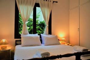 a bedroom with a bed with white pillows and a window at Anthi's Villa in Achladies