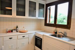 a kitchen with white cabinets and a sink at Anthi's Villa in Achladies