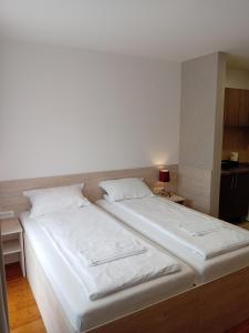 1 dormitorio con 2 camas con sábanas blancas en Apartment Atina, en Subotica