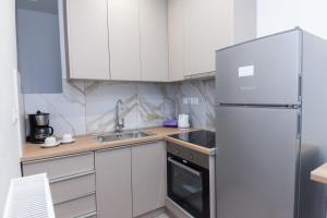 a kitchen with white cabinets and a stainless steel refrigerator at Stylish Brand New Apt near Megaro Mousikis in Athens