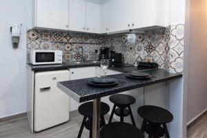uma cozinha com um balcão com bancos e um micro-ondas em Metaxourgio 2 Bedroom Gem for Urban Explorers em Atenas
