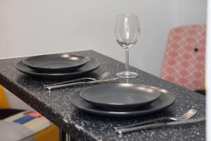 uma mesa com pratos pretos e um copo de vinho em Metaxourgio 2 Bedroom Gem for Urban Explorers em Atenas