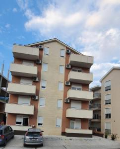 un edificio alto con coches estacionados frente a él en Apartman Maja en Igalo