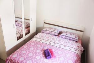 Dormitorio pequeño con cama con sábanas rosas y espejo en Apartman Maja en Igalo