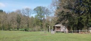 einen Pavillon auf einem Feld neben einem Baum in der Unterkunft Cabanes des Landes- cabane sur pilotis in Saint-Éloy-les-Tuileries
