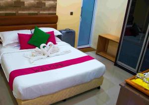 Schlafzimmer mit einem Bett mit roten und grünen Kissen in der Unterkunft Veyo Retreat in Veymandoo