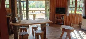 cocina con mesa de madera y taburetes en una habitación en Cabanes des Landes- cabane sur pilotis, en Saint-Éloy-les-Tuileries