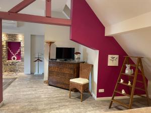 a living room with purple walls and a tv at Les Myosotis Chambres d'hôtes - Sarreguemines in Zetting