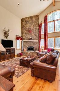 a living room with a couch and a stone fireplace at Lazy Fox Lodge in National Forest View in Breckenridge