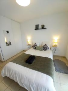 - une chambre avec un grand lit blanc et deux lampes dans l'établissement Cocon reposant à 10min du centre de Bordeaux, à Lormont